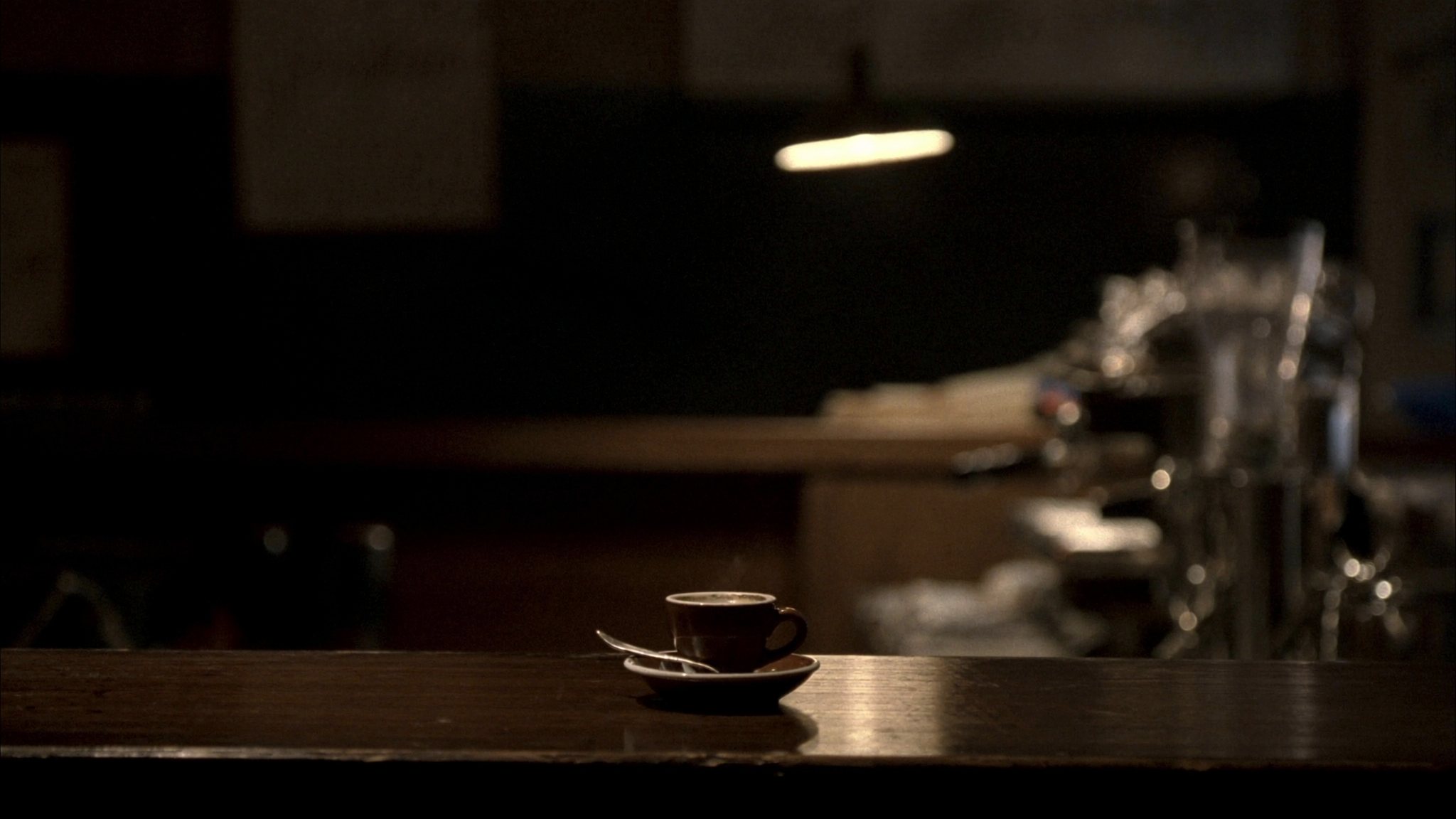 A single espresso cup on a dark café counter at night